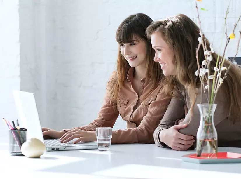 Two women working on computer smiling